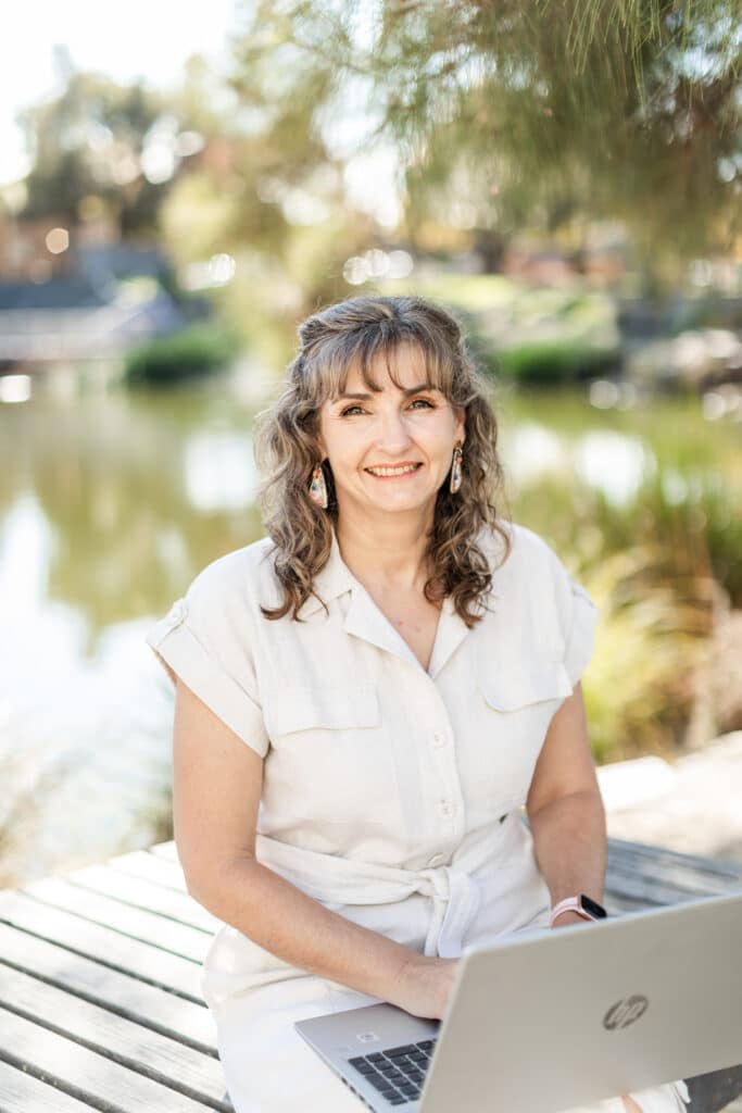 Photo of ISO Matters Founder and CEO, Justeen Kirk sitting by a lagoon with a laptop